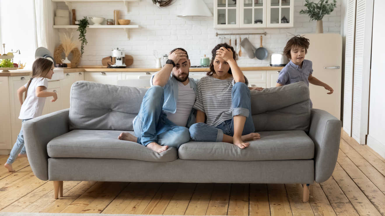 Picture of couple looking stressed as there kids run arround them