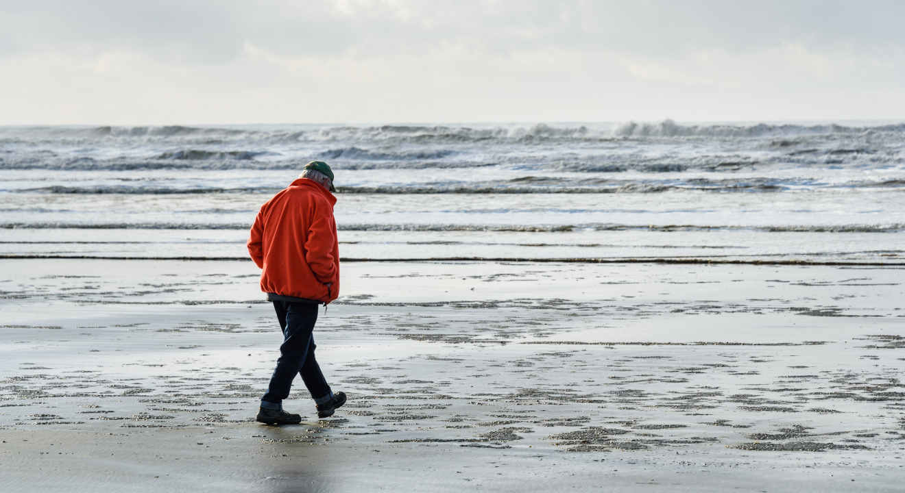 Man walking on beach alone on a cold winter day